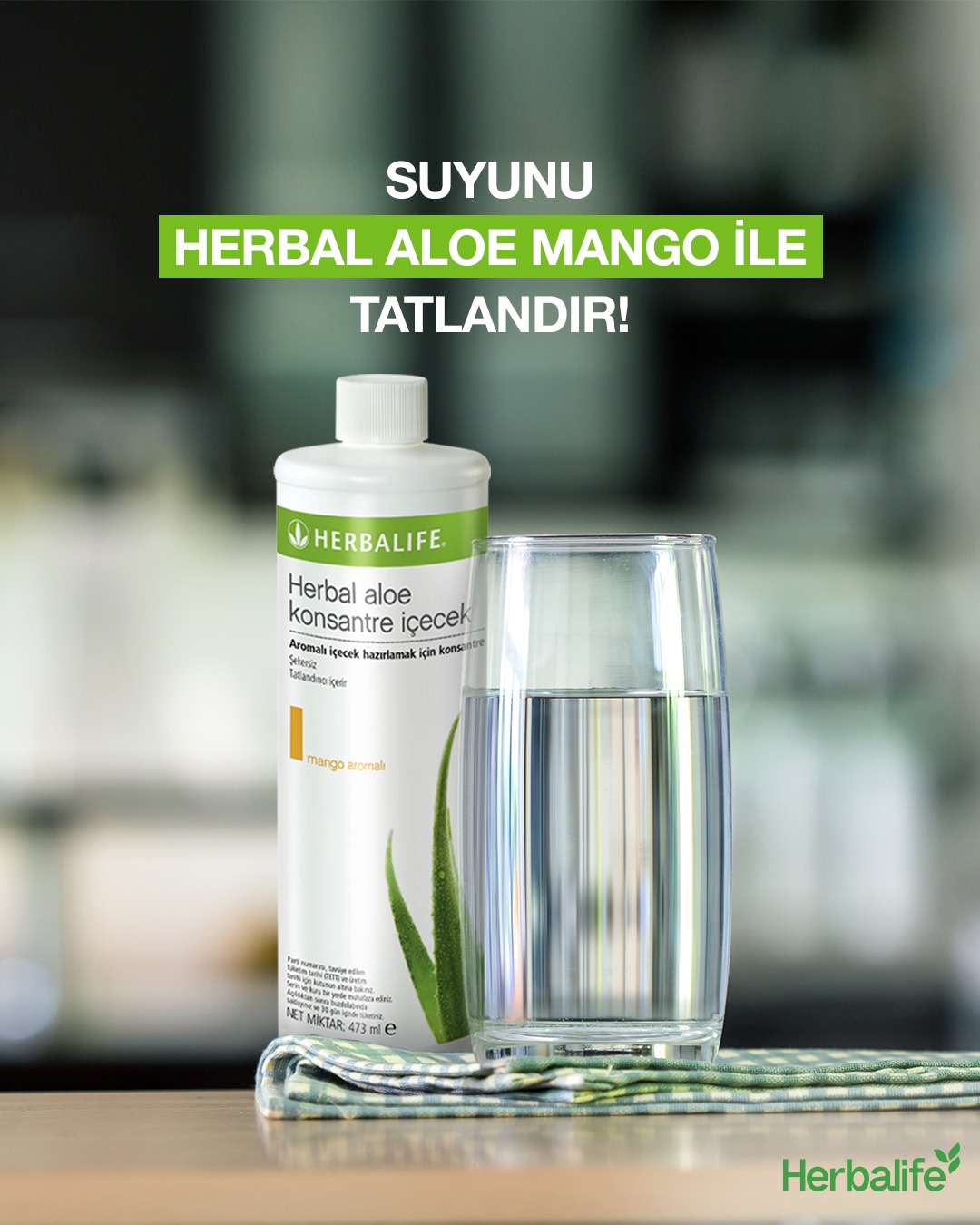 Herbalife Herbal Aloe Konsantre İçecek Mango Aromalı Herbalife Aloe Konsantre İçecek kutusu ve yanında aloe vera suyu ile tatlandırılmış bir bardak su